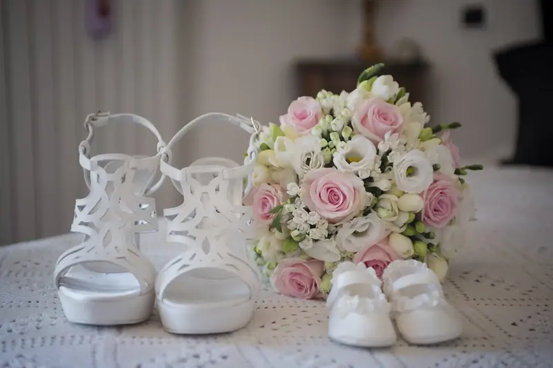 Sandali bianchi accanto al bouquet di rose rosa